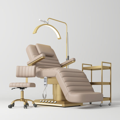 Beige and gold medical examination chair with a lamp and side table on a white background